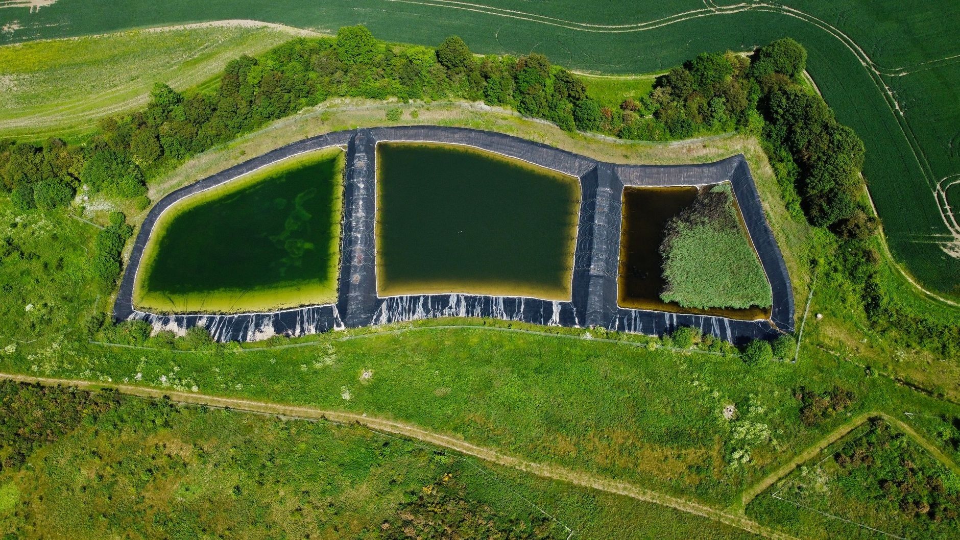 Luchtfoto van drie met water gevulde retentiebekkens in het groen