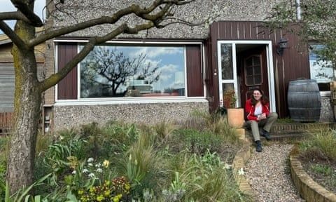Groene voortuin zonder tegels met zittende vrouw bij de woning